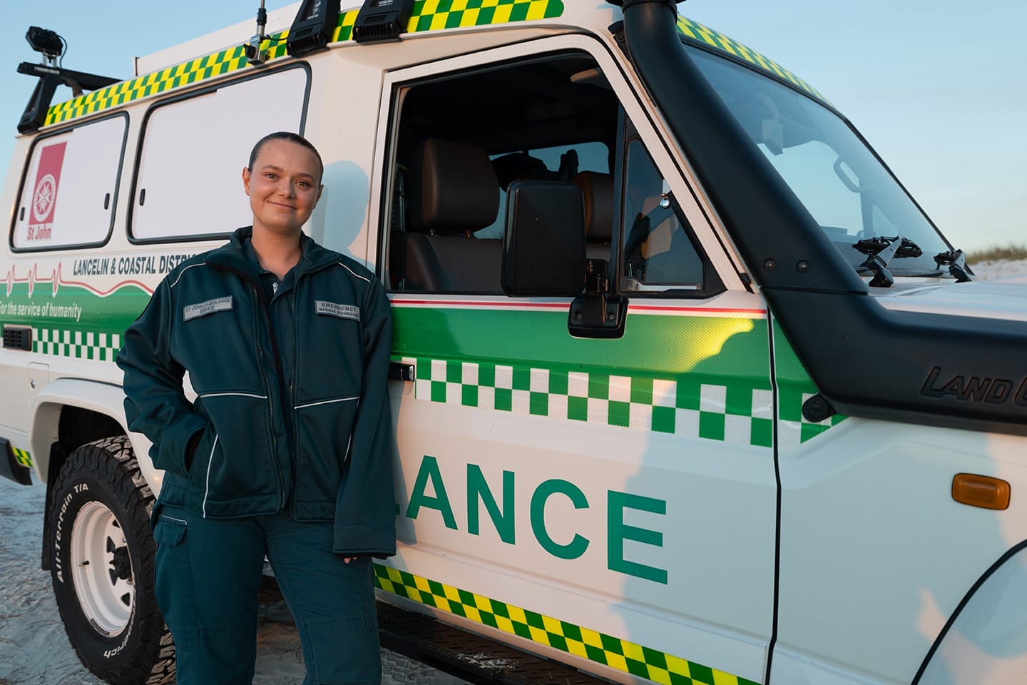 A person in uniform stands in front of an ambulance troop carrier.
