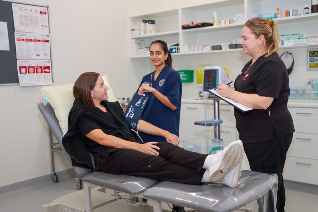 Two healthcare workers support a patient in a hospital setting.