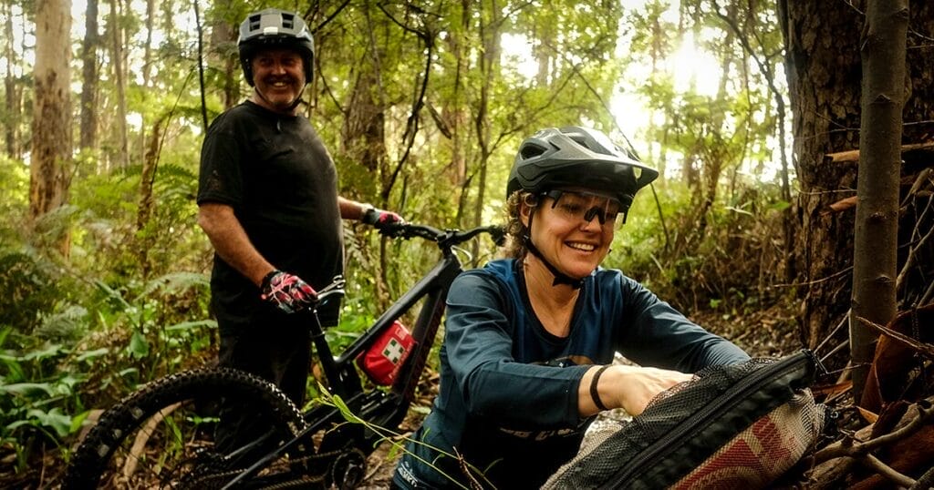 A man and a woman with mountain bikes take a break on the trail.